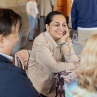Three event guests sitting at table and chatting with each other